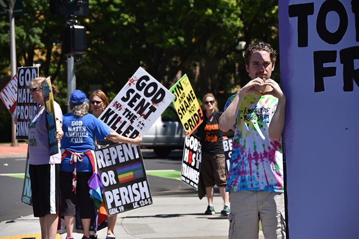Liam Worrell-Olson, right, makes a heart with his hands while standing in front of picketers from the Westboro Baptist Church, who protested at the J Street entrance to Sac State on Tuesday, May 8. The Westboro Baptist Church is a Kansas-based Christian fundamentalist group known for its inflammatory anti-LGBT speech.